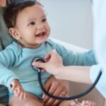 Pediatrician examining a smiling child during a regular health checkup in a bright clinic.